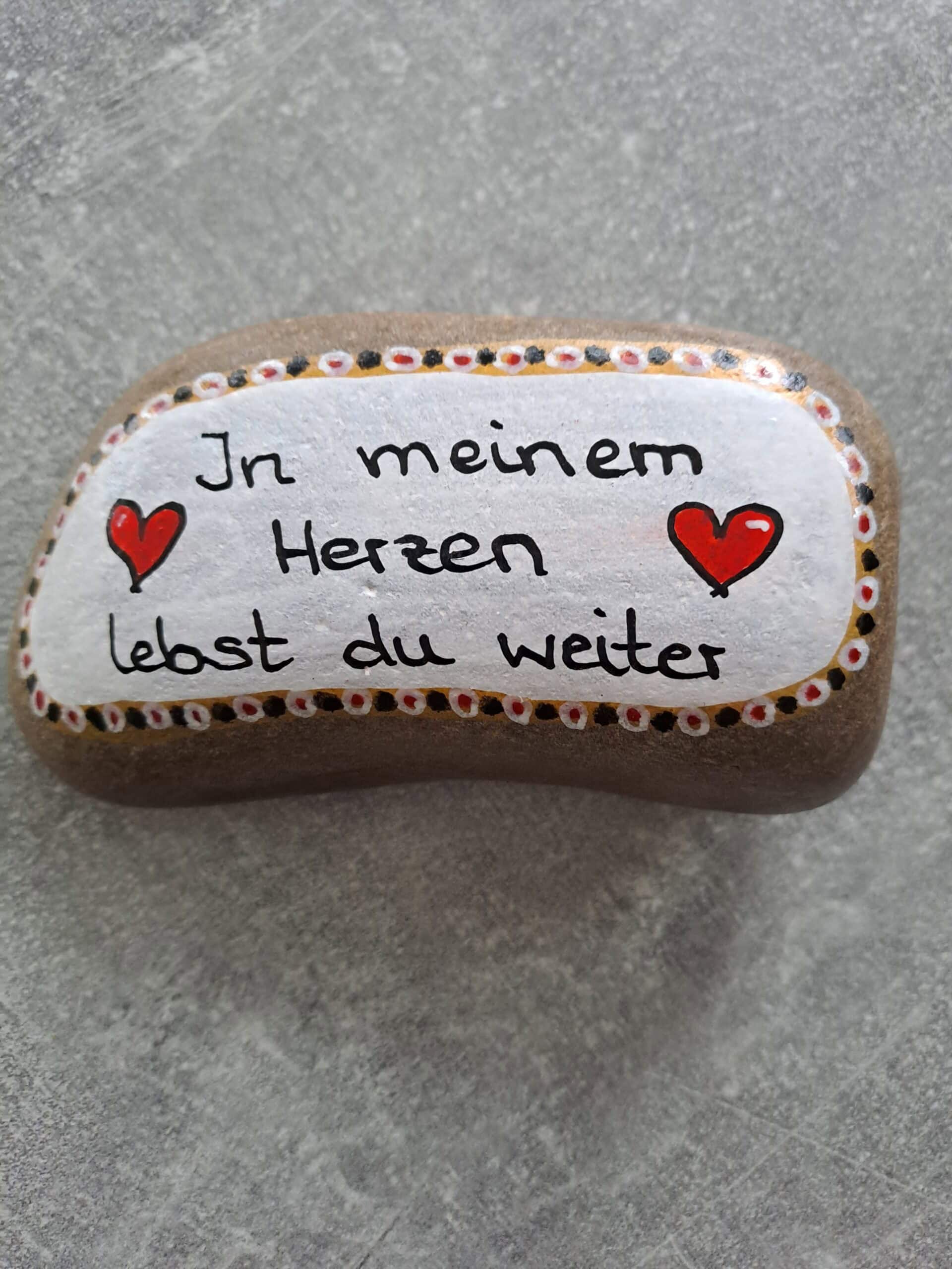 In meinem Herzen lebst du weiter Spruch Stein auf grauen Stein geschrieben mit weißem Hintergrund und mehrfarbiger Bordüre außen herum