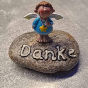 grauer Stein, darauf ist ein hellblauer Schutzengel Danke nachtleuchtend als Spruch