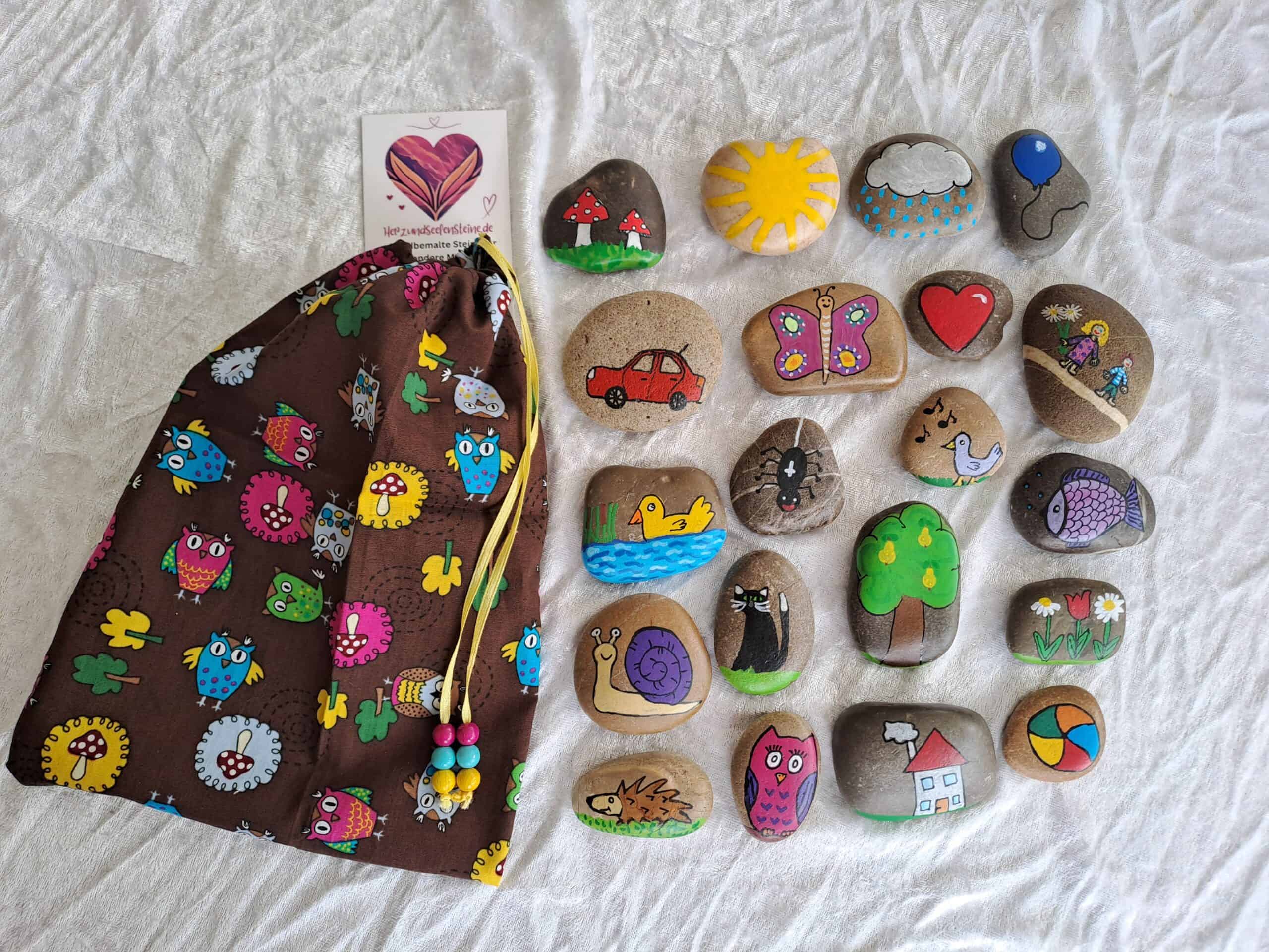 Erzählsteine 20 bunte Motive in braunem Baumwollbeutel mit bunten Motiven. Steinmotive sind Auto, Regenwolke, Luftballon, Katze, Ball, Haus, Sonne, Vogel, Ente, Blumen, Schmetterling, Spinne, Fliegenpilze. Schnecke, Herz, Kinder, Fisch, Birnbaum, Eule, Igel