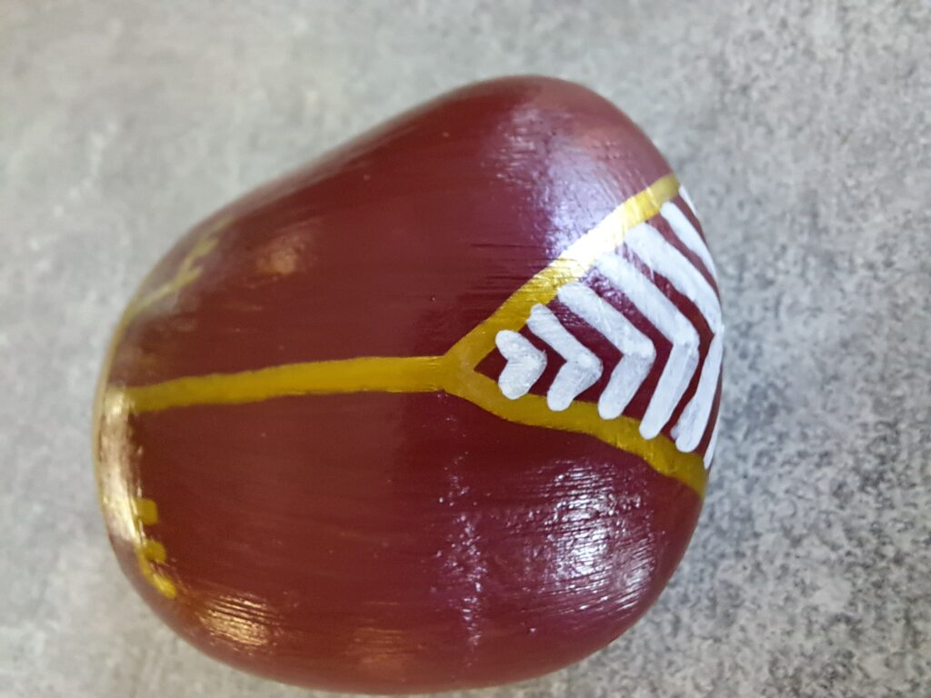 Maikäfer auf Stein malen, diese Variante mit weißen Zick-Zack-Linien auf braunem Hintergrund