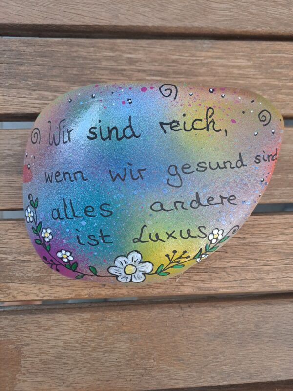 Spruch-Stein Gesundheit ist ein kunterbunter großer Stein mit dem Spruch "Wir sind reich, wenn wir gesund sind, alles andere ist Luxus. Er ist verziert mit einer schönen Blumenbordüre unten entlang